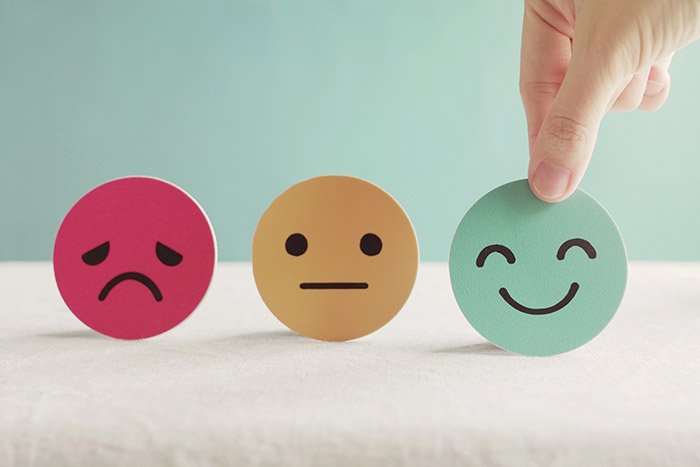 Eine Hand greift nach einem glücklichen Papier-Emoji
