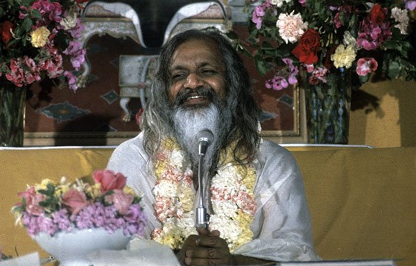 Maharishi Maesh Yogi, umgeben von Blumensträußen, bei einer Lecture in den siebziger Jahren