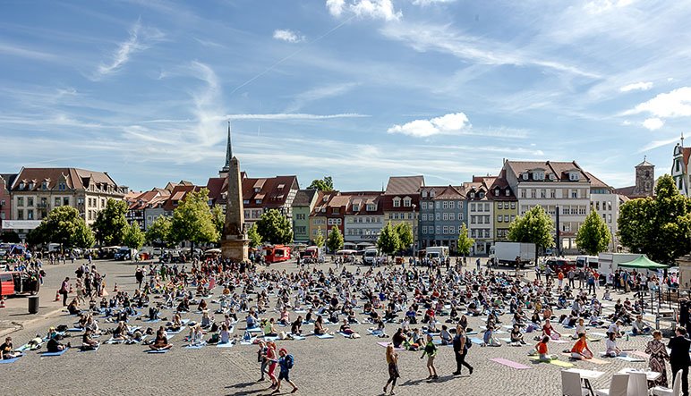 Hunderte Teilnehmer auf dem Erfurter Domplatz sitzen beim Weltyogatag auf ihren Yogamatten